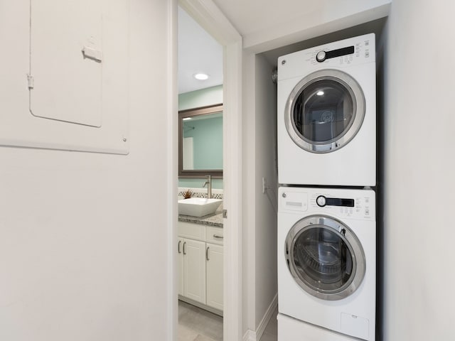 laundry room with electric panel, sink, and stacked washer and clothes dryer