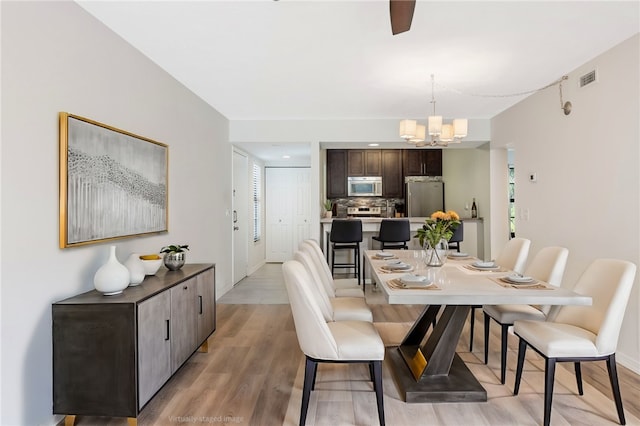 dining area with light hardwood / wood-style flooring and a chandelier