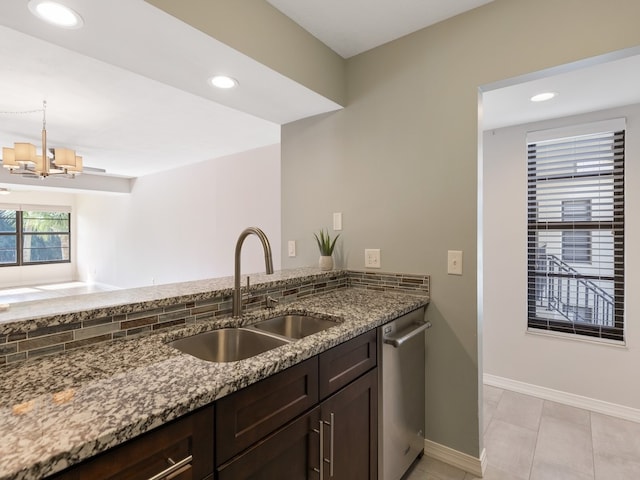 kitchen with dark stone counters, a notable chandelier, sink, light tile patterned floors, and stainless steel dishwasher