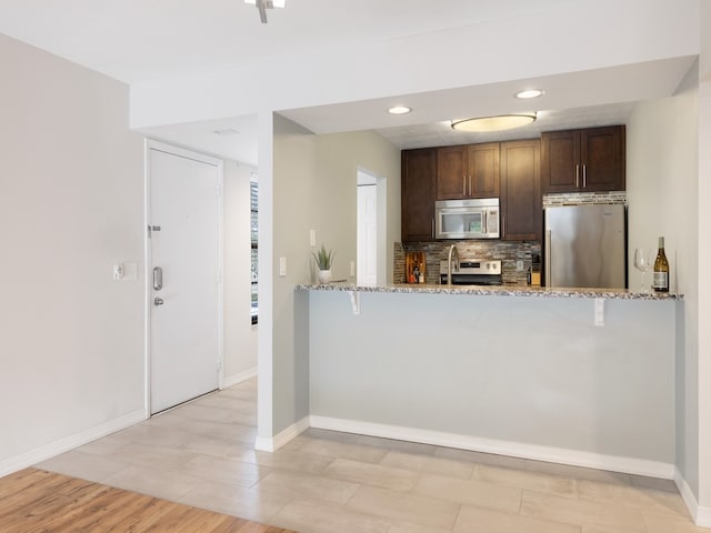 kitchen featuring light stone countertops, kitchen peninsula, and stainless steel appliances