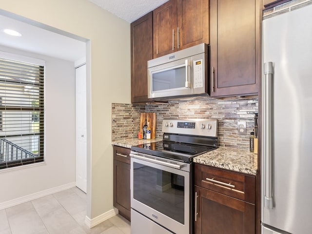 kitchen with stainless steel appliances, light tile patterned floors, light stone counters, and tasteful backsplash