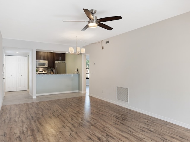 interior space featuring hardwood / wood-style floors and ceiling fan with notable chandelier