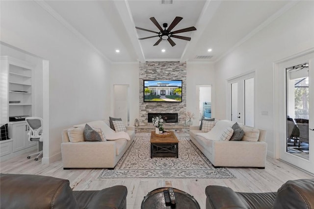 living room with crown molding, a fireplace, ceiling fan, and light wood-type flooring