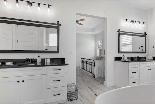 bathroom featuring vanity, hardwood / wood-style flooring, a bathing tub, and ceiling fan