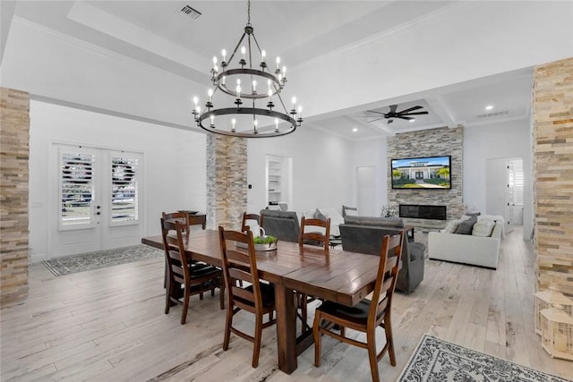 dining room with ceiling fan, a fireplace, light hardwood / wood-style floors, french doors, and beamed ceiling