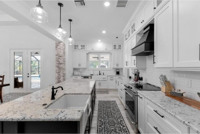 kitchen with sink, stainless steel electric range, an island with sink, custom range hood, and white cabinets