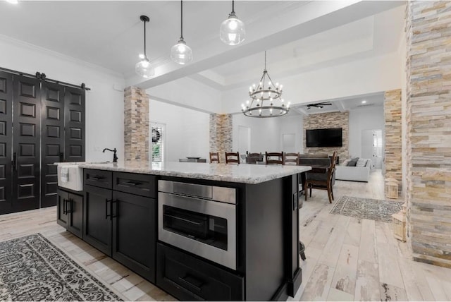 kitchen featuring crown molding, sink, hanging light fixtures, and a center island with sink