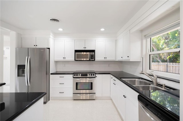 kitchen with sink, white cabinets, decorative backsplash, and appliances with stainless steel finishes