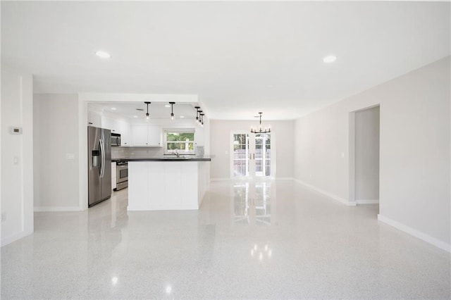 kitchen with hanging light fixtures, appliances with stainless steel finishes, white cabinets, an inviting chandelier, and decorative backsplash