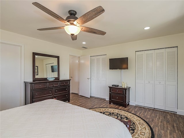 bedroom featuring dark hardwood / wood-style floors, ceiling fan, and multiple closets