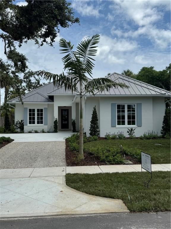 ranch-style home with stucco siding, a metal roof, driveway, and a standing seam roof