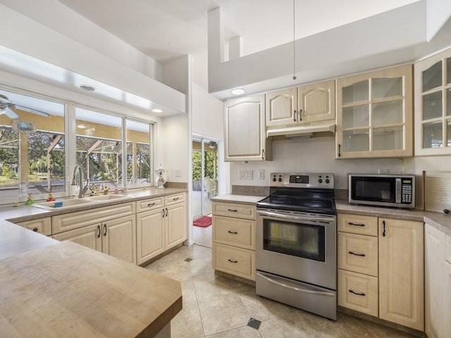 77 Joy Haven Dr, Sebastian, FL 32958 - kitchen featuring stainless steel appliances, under cabinet range hood, light brown cabinetry, glass insert cabinets, and light countertops