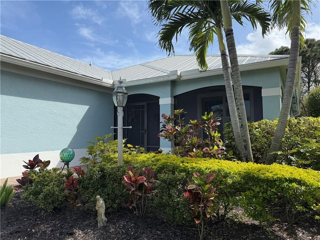 doorway to property featuring stucco siding and metal roof