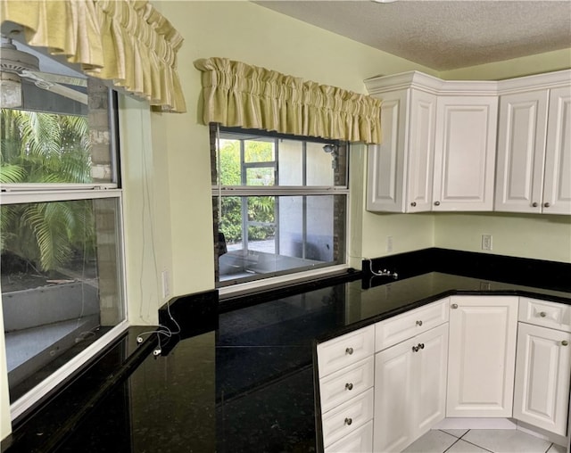 kitchen with a textured ceiling, light tile patterned floors, and white cabinets