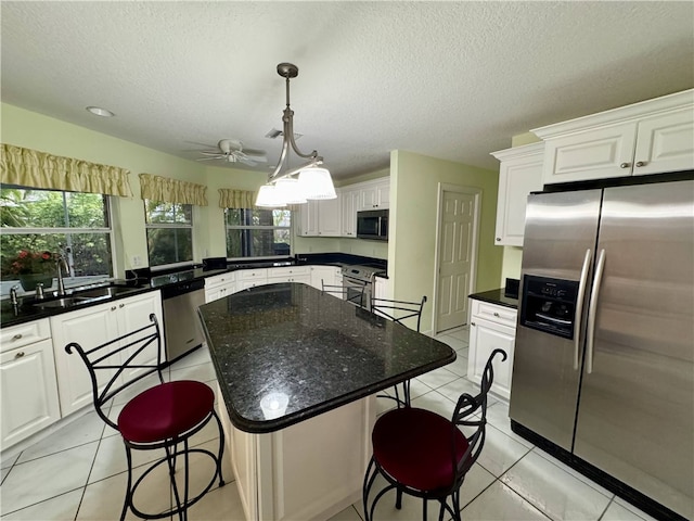 kitchen with light tile patterned floors, stainless steel appliances, a breakfast bar area, and a sink