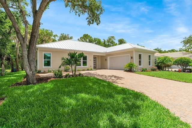 1090 Buckhead Dr SW, Vero Beach, FL 32968 - ranch-style house featuring an attached garage, decorative driveway, a front yard, metal roof, and a standing seam roof