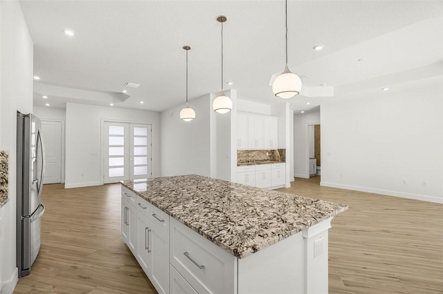 1090 Buckhead Dr SW, Vero Beach, FL 32968 - kitchen with freestanding refrigerator, light wood-style flooring, baseboards, french doors, and white cabinetry