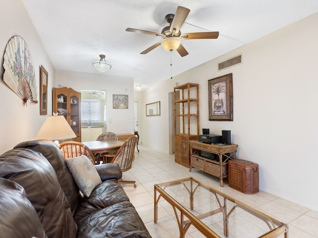 living room featuring light tile patterned flooring, ceiling fan, and a textured ceiling