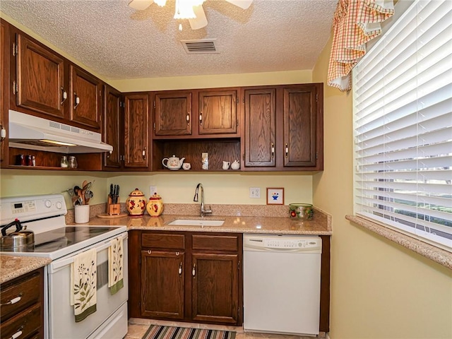 kitchen featuring sink, white appliances, ceiling fan, light stone countertops, and a textured ceiling