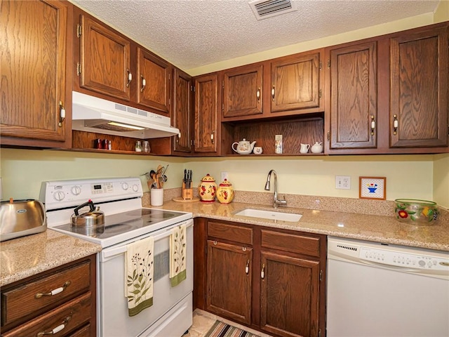 kitchen with white appliances, light stone countertops, sink, and a textured ceiling