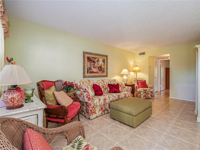 tiled living area with visible vents, a textured ceiling, and baseboards