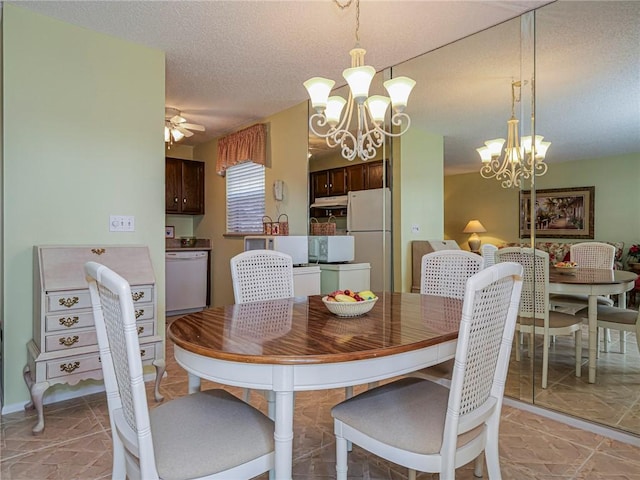 dining area with ceiling fan with notable chandelier and a textured ceiling