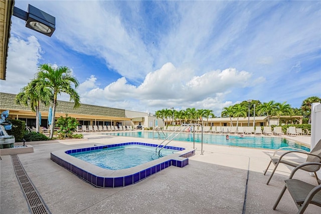 community pool with a patio and a hot tub