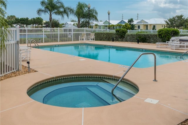 view of swimming pool featuring a hot tub and a patio area