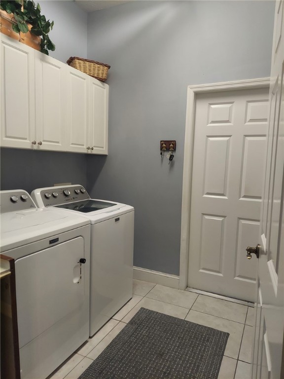 washroom featuring light tile patterned flooring, cabinets, and washer and dryer