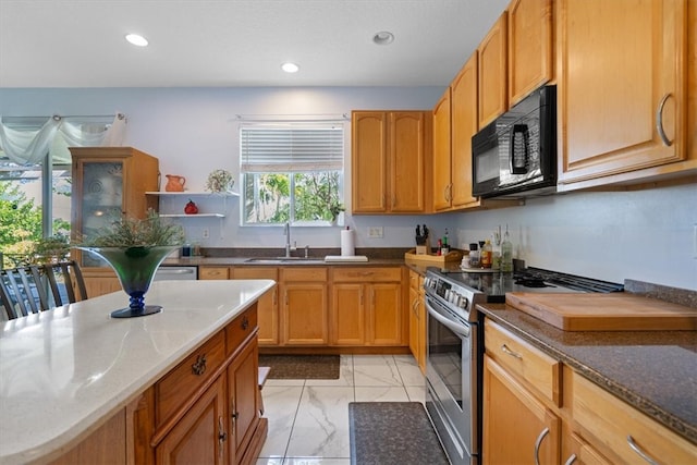 kitchen featuring light stone counters, sink, and stainless steel range oven