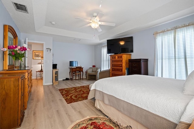 bedroom featuring a tray ceiling, light hardwood / wood-style flooring, and ceiling fan