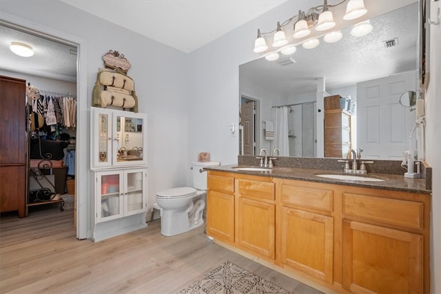 bathroom featuring a shower with shower curtain, a textured ceiling, vanity, hardwood / wood-style floors, and toilet