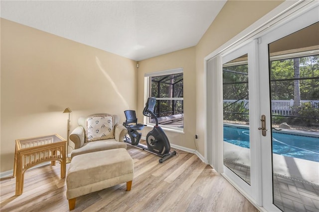 living area featuring baseboards, french doors, wood finished floors, and a healthy amount of sunlight