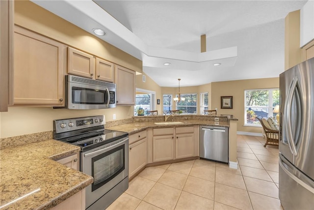 kitchen with a wealth of natural light, appliances with stainless steel finishes, light brown cabinets, a sink, and a peninsula