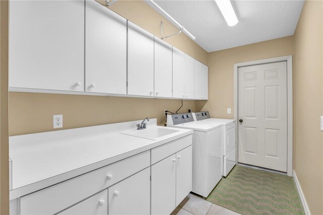 clothes washing area with a sink, cabinet space, baseboards, and washer and dryer