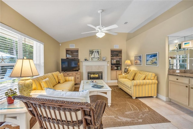 living room featuring vaulted ceiling, light tile patterned flooring, a glass covered fireplace, and visible vents