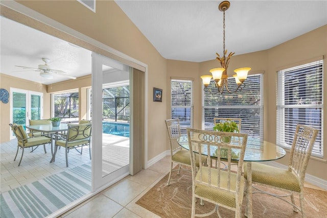 dining space featuring light tile patterned floors, vaulted ceiling, ceiling fan with notable chandelier, and baseboards