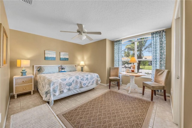 tiled bedroom featuring a ceiling fan, visible vents, a textured ceiling, and baseboards