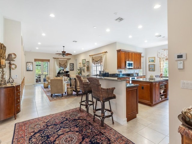 kitchen featuring a kitchen island, a breakfast bar area, range, light tile patterned floors, and kitchen peninsula