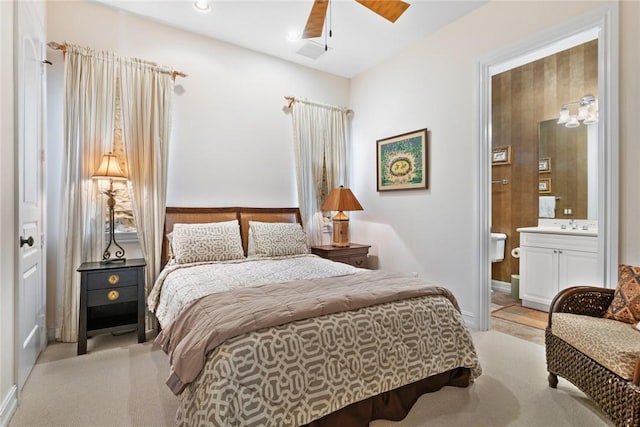 bedroom featuring ceiling fan, connected bathroom, and light colored carpet