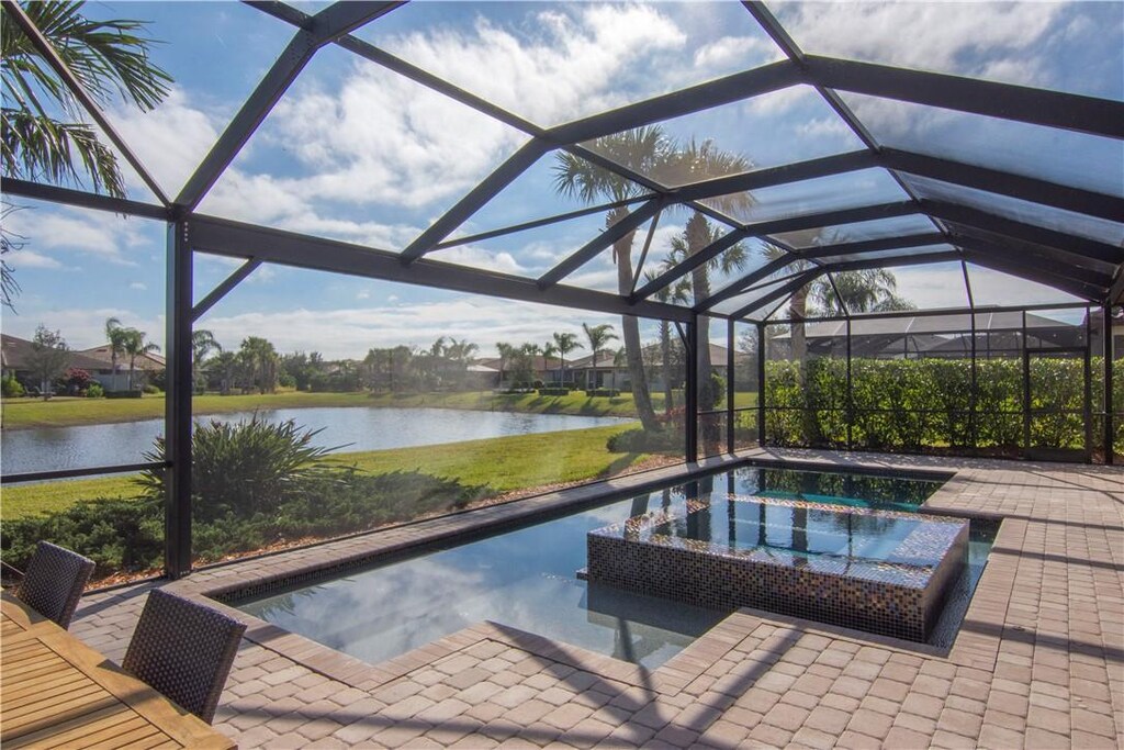 view of swimming pool featuring glass enclosure and a water view