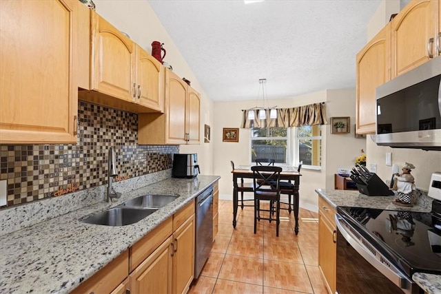 kitchen with light stone countertops, appliances with stainless steel finishes, backsplash, sink, and decorative light fixtures