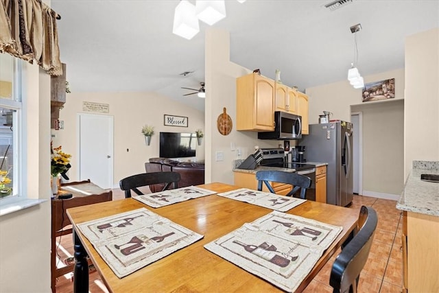 dining area with ceiling fan, light tile patterned flooring, and vaulted ceiling