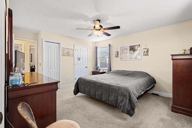 carpeted bedroom with ceiling fan and two closets