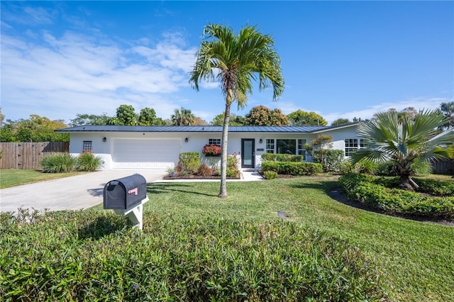 ranch-style house featuring an attached garage, fence, a front yard, metal roof, and driveway