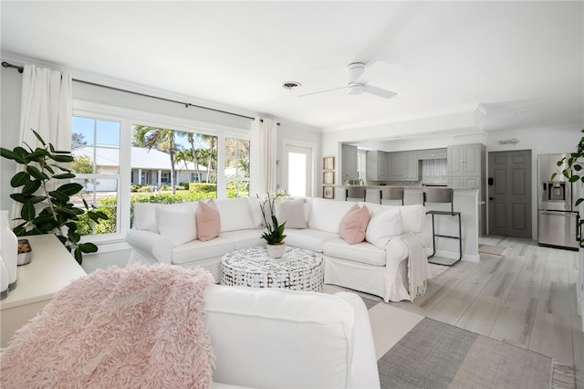 living area featuring light wood finished floors, plenty of natural light, visible vents, and a ceiling fan