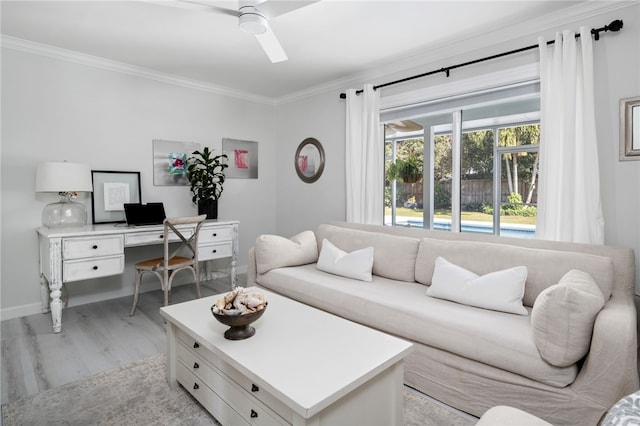 living area featuring a ceiling fan, crown molding, light wood-style floors, and baseboards