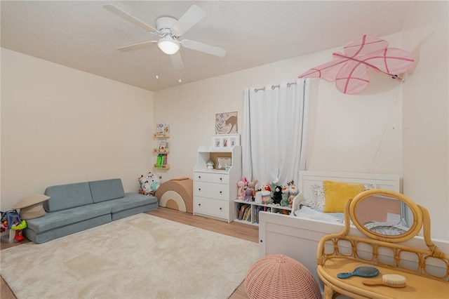 sitting room with ceiling fan, light carpet, and a textured ceiling