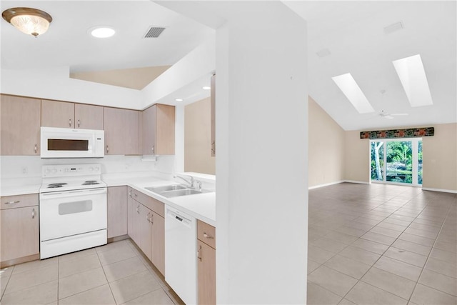 kitchen featuring sink, white appliances, light tile patterned floors, lofted ceiling with skylight, and light brown cabinets