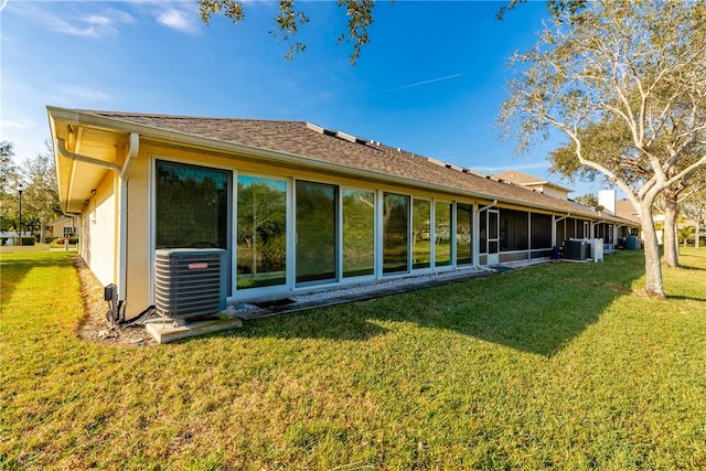 back of house with cooling unit and a lawn